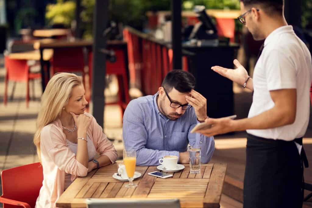 Nespokojný hostia v reštaurácii a čašník rieši problém pre Edu-management.sk